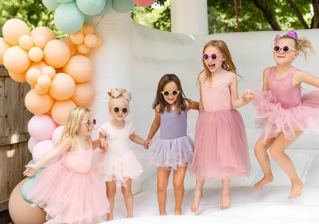 Children joyfully bouncing in a colorful inflatable bounce house at a backyard party.