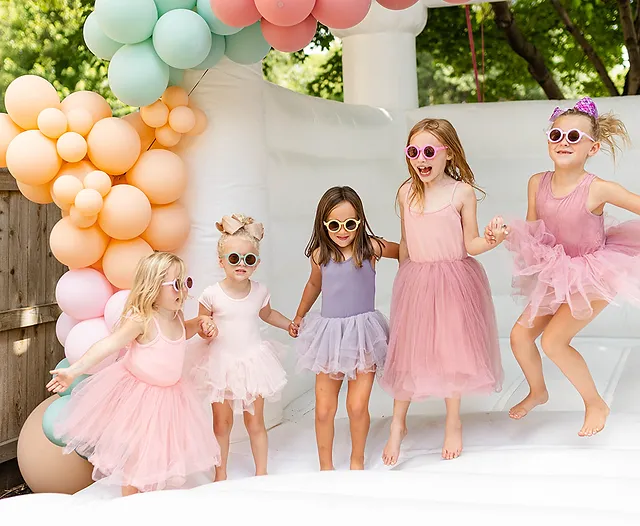 Children joyfully bouncing in a colorful inflatable bounce house at a backyard party.